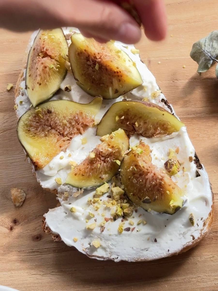 fresh figs and chopped pistachios arranged on cottage cheese toast