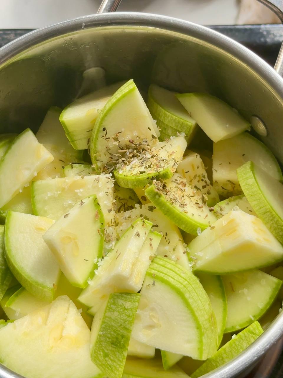 adding zucchini, Italian herbs, and salt to the soup