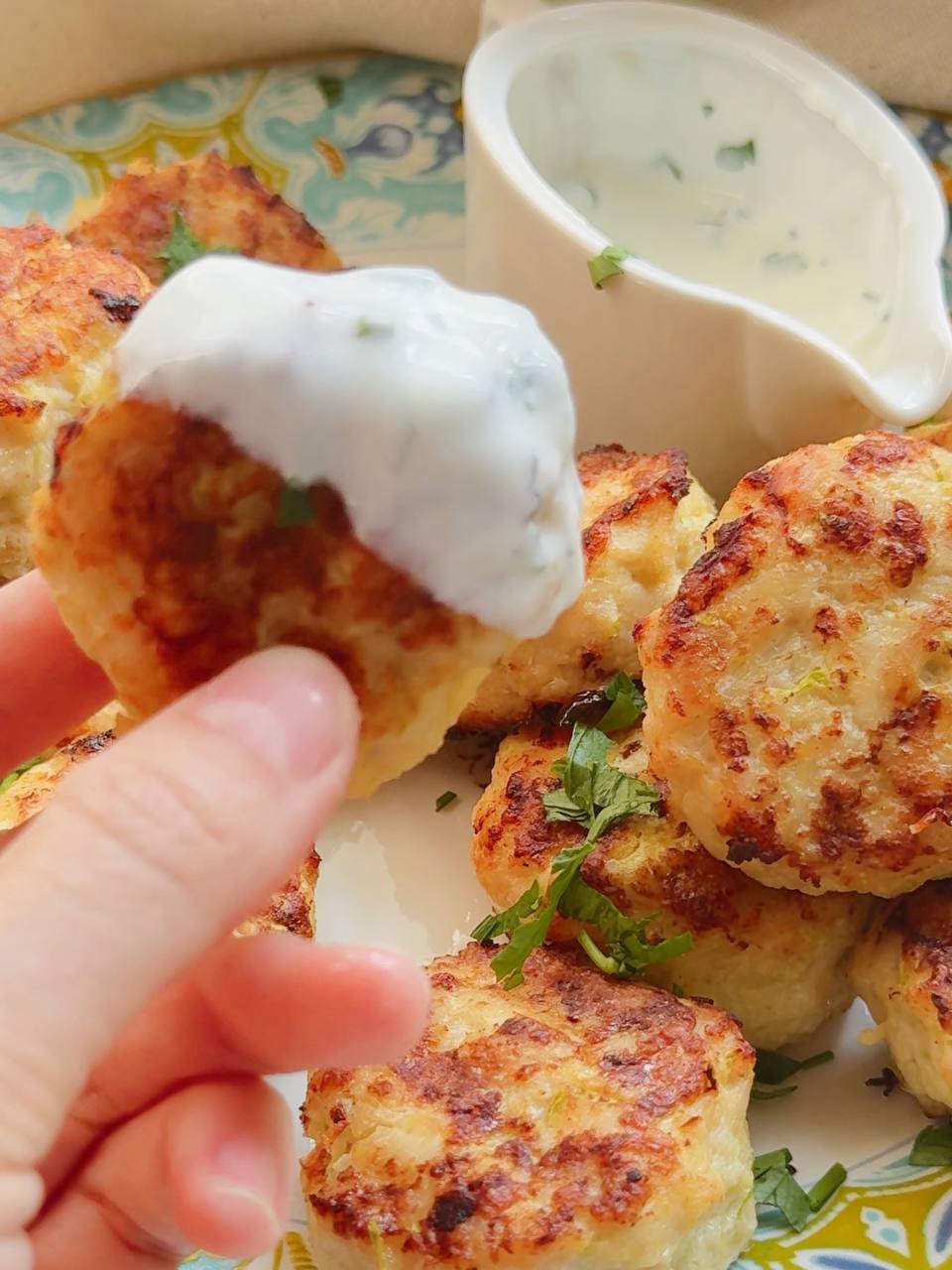 dipping a chicken zucchini patty into garlic yogurt sauce