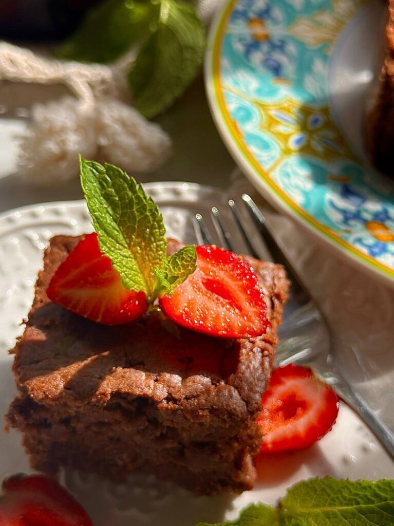 close-up of fudgy chocolate zucchini brownies with strawberries and mint