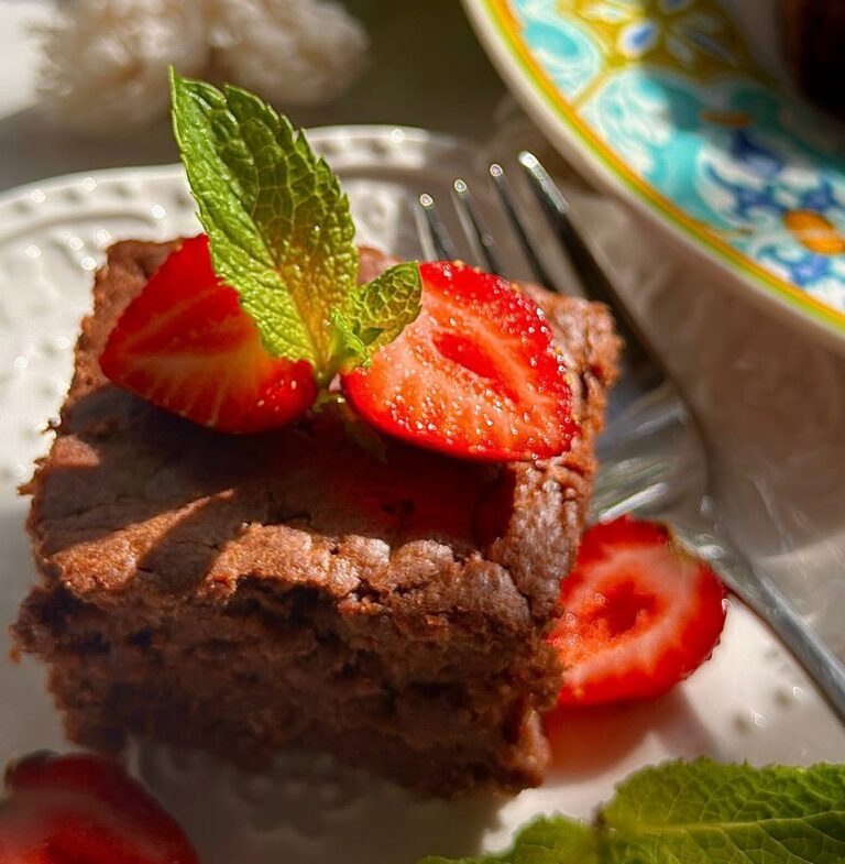 close-up of fudgy chocolate zucchini brownies with strawberries and mint