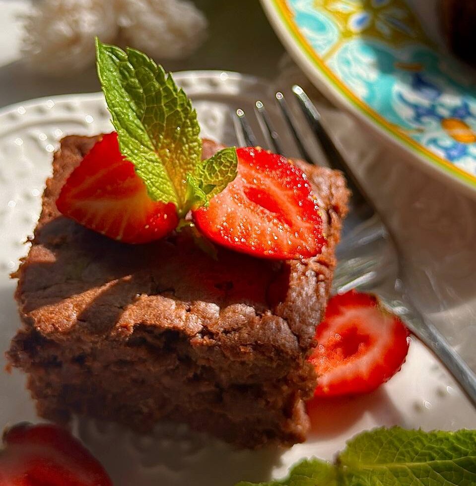 close-up of fudgy chocolate zucchini brownies with strawberries and mint