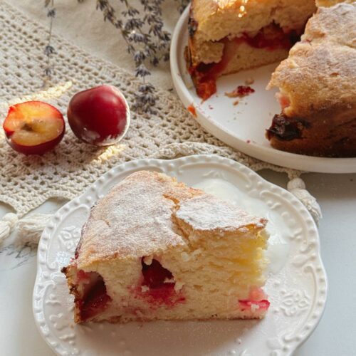 Slice of moist Greek yogurt plum cake with fresh plums