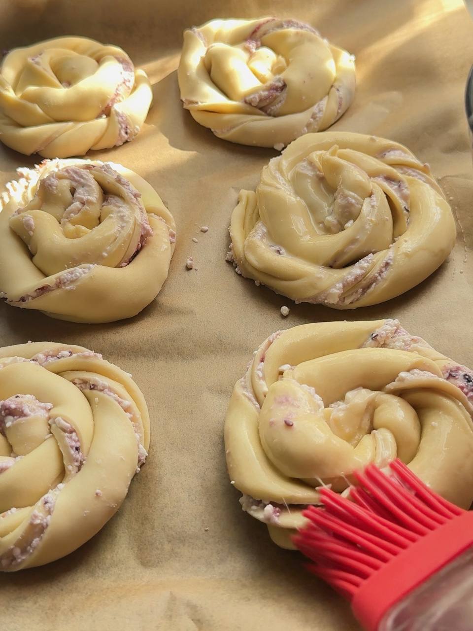 Shaped cottage cheese buns brushed with egg wash before baking