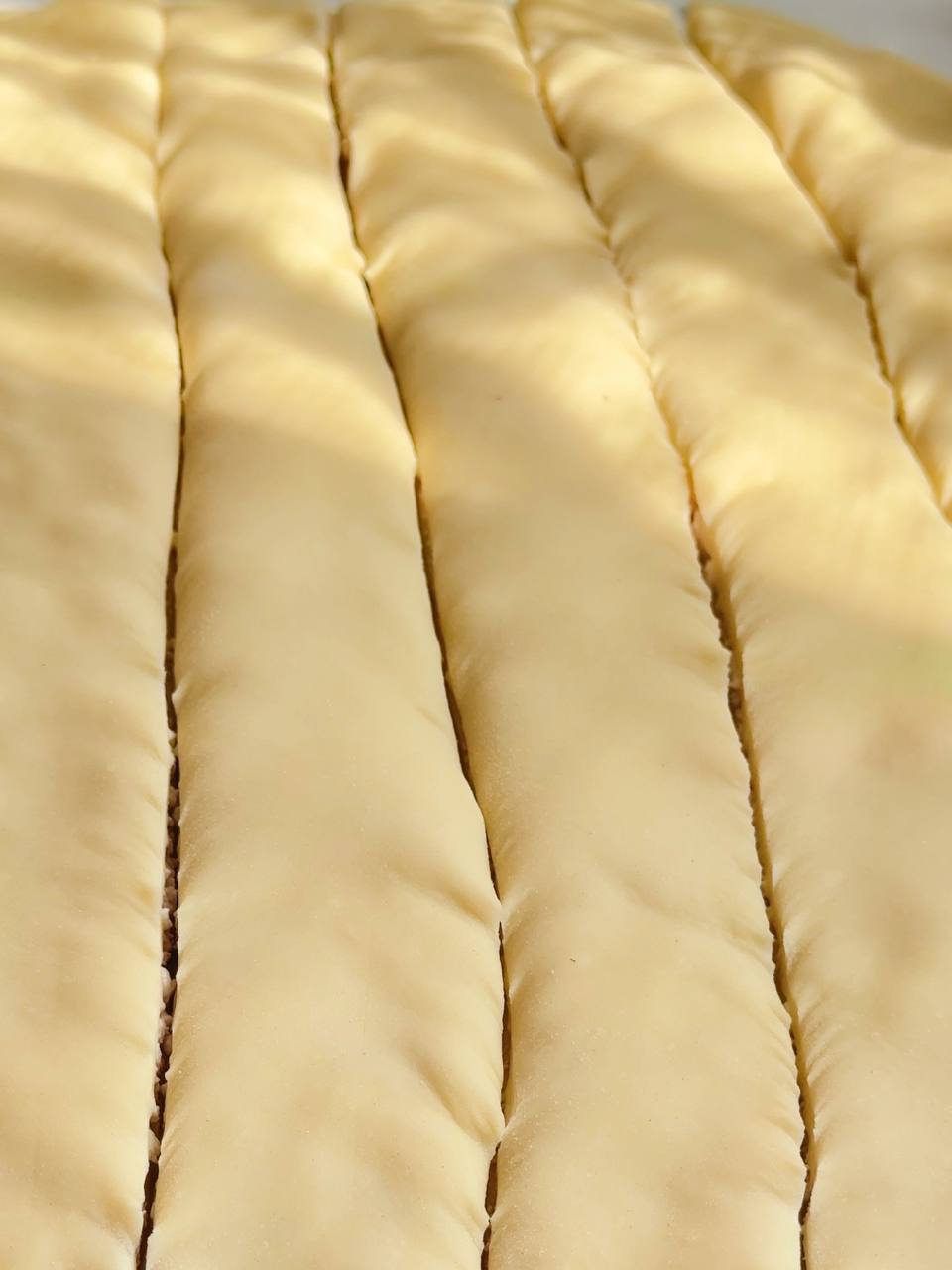 Filled puff pastry cut into long strips for shaping cottage cheese buns