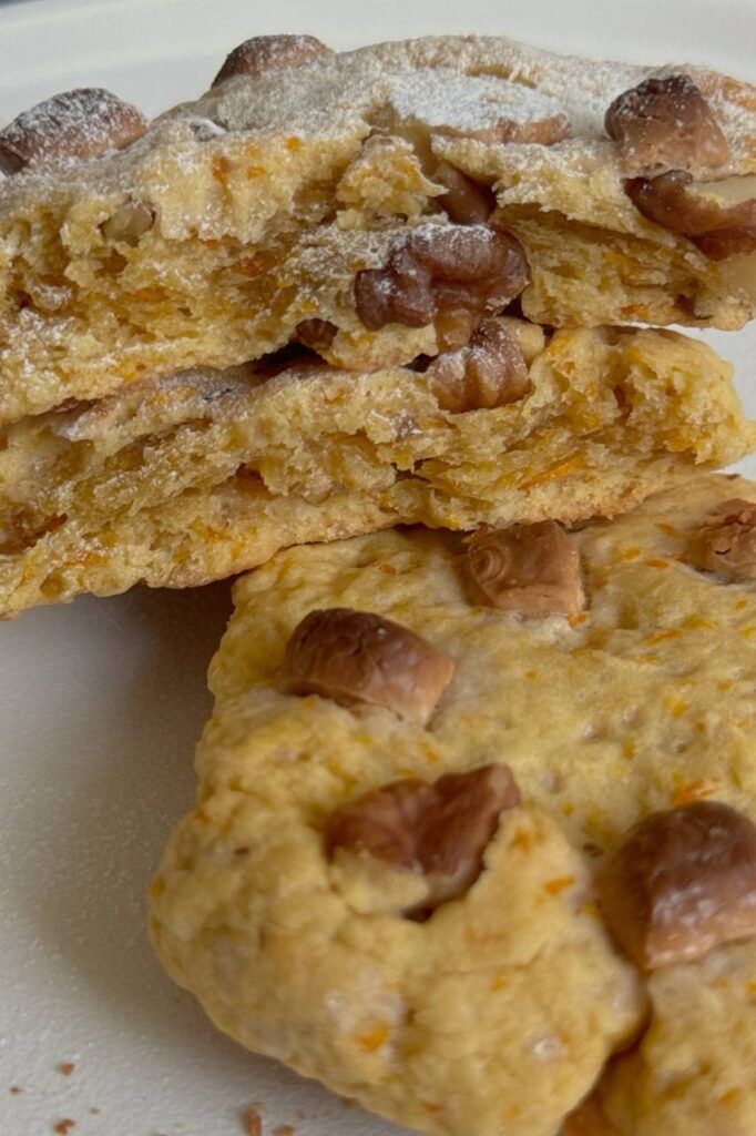 Close-up of a broken carrot cake cookie showing its soft center, walnuts, and grated carrot