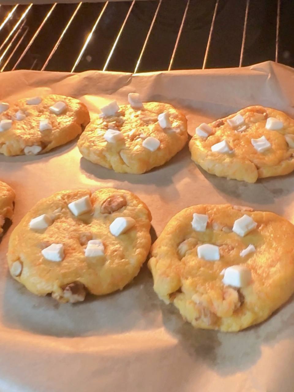 Carrot cake cookies topped with white chocolate baking in the oven