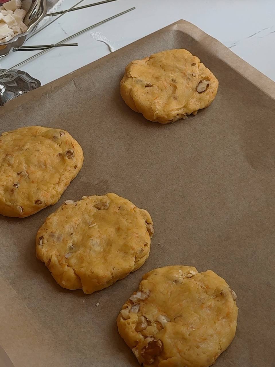 Thick carrot cake cookies shaped and arranged on a parchment-lined baking sheet
