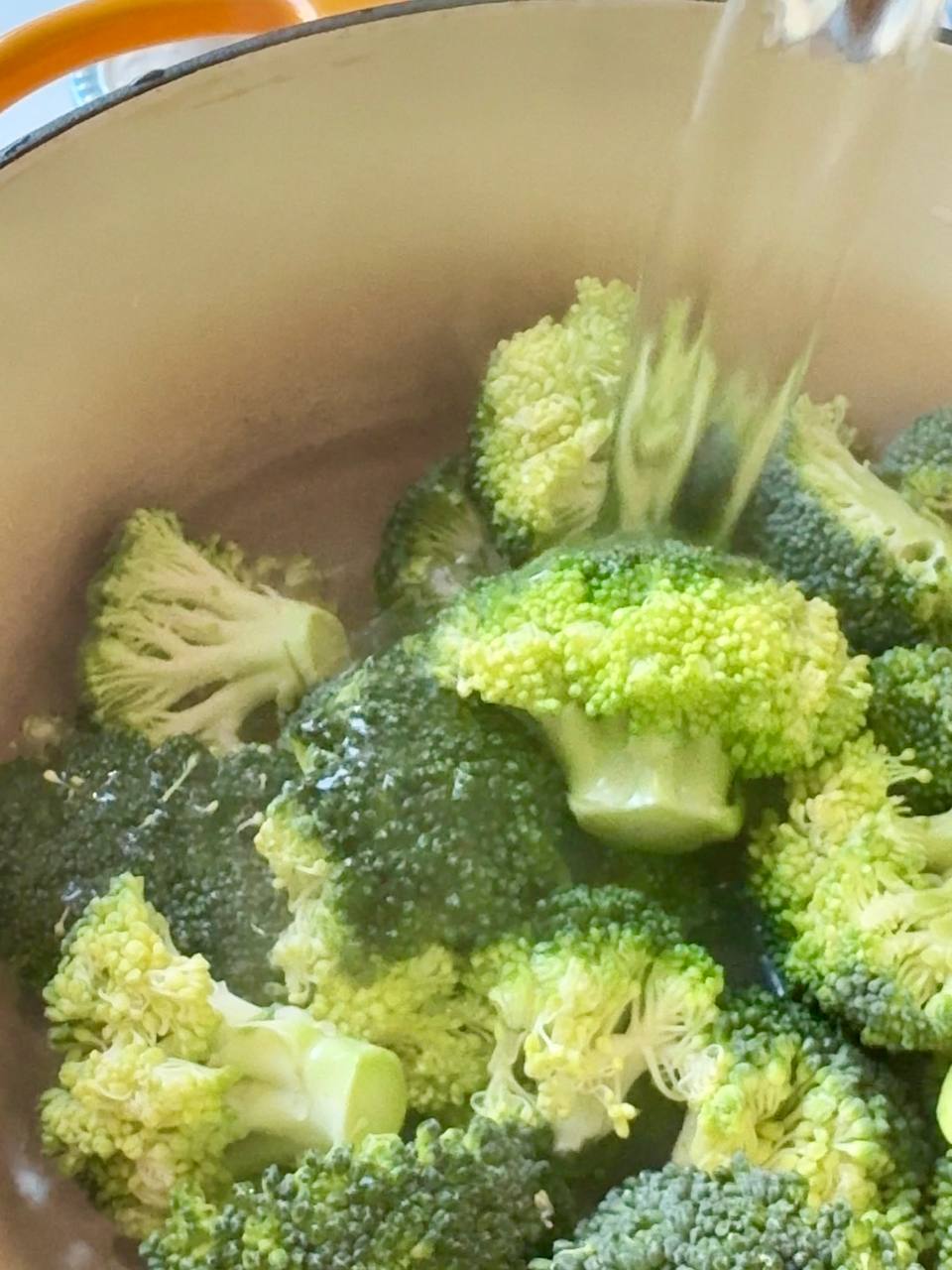 Fresh broccoli florets boiling in a pot of water until tender.