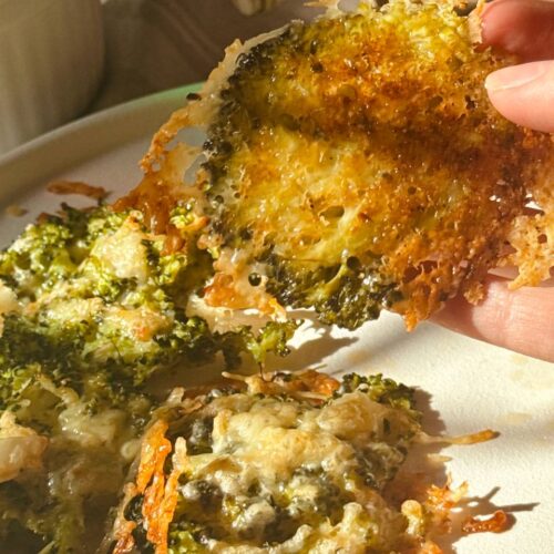 Close-up of crispy Parmesan broccoli being lifted from the baking sheet with a spatula.