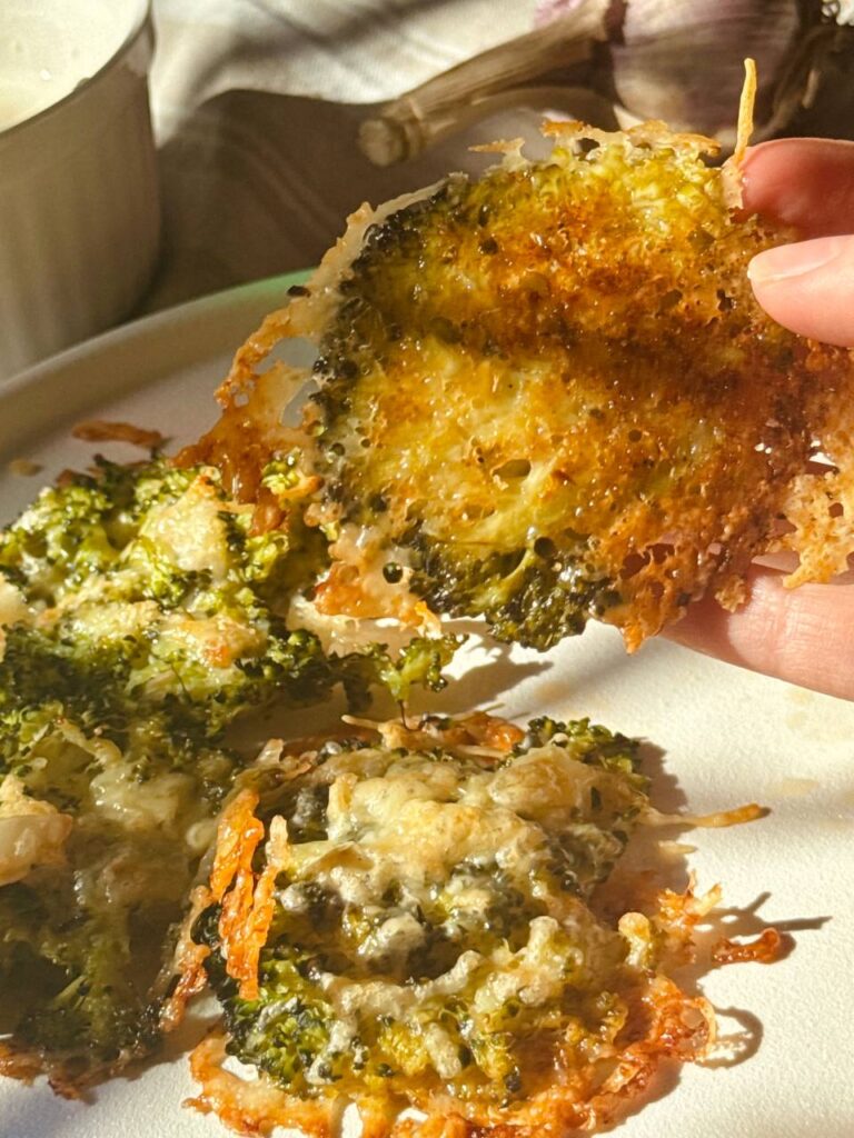 Close-up of crispy Parmesan broccoli being lifted from the baking sheet with a spatula.