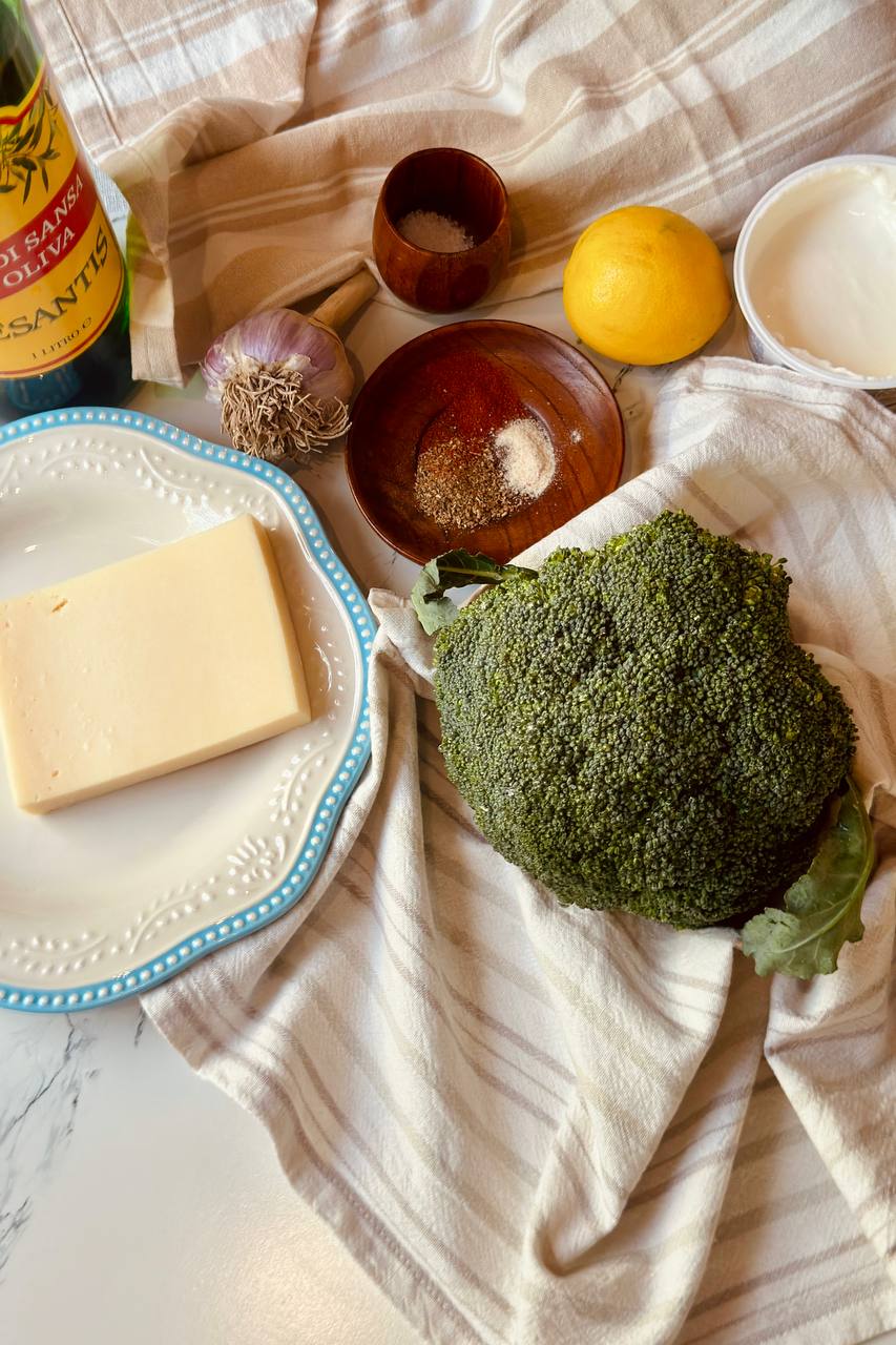 Ingredients for garlic Parmesan broccoli with fresh broccoli, Parmesan, garlic, olive oil, lemon, and Greek yogurt.