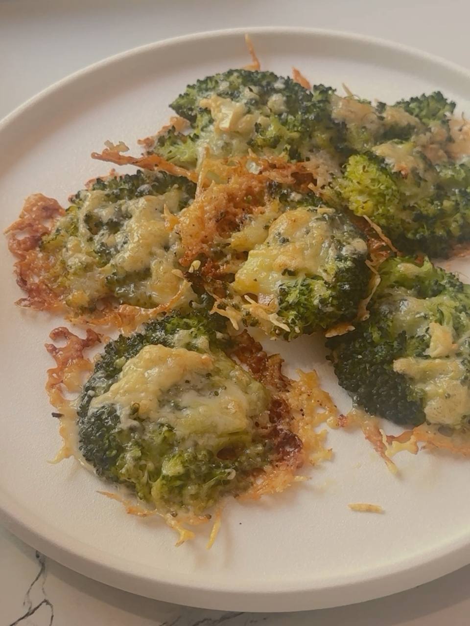 Crispy garlic Parmesan broccoli with golden cheese edges on a serving plate.