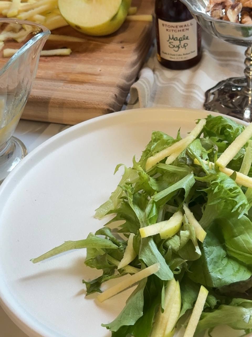Fresh mixed salad greens topped with thinly sliced green apple, ready for walnuts and honey mustard dressing.