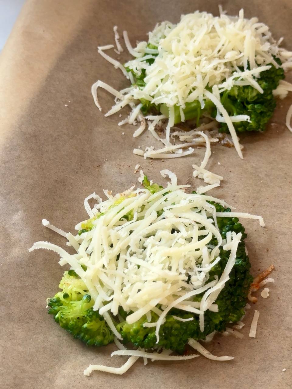 Smashed broccoli topped with grated Parmesan cheese before baking.